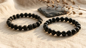 Natural black tourmaline and black obsidian bracelets resting on linen fabric for protection and grounding.