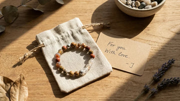 Handcrafted gemstone bracelet in a linen gift pouch with a handwritten card for spiritual gifting.